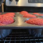 close-up image of small red velvet cakes in a pan sitting on an oven.
